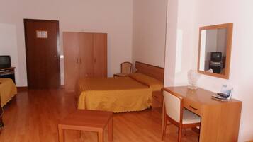 A small, tidy room with a bed, a desk, a chair, and a wardrobe.