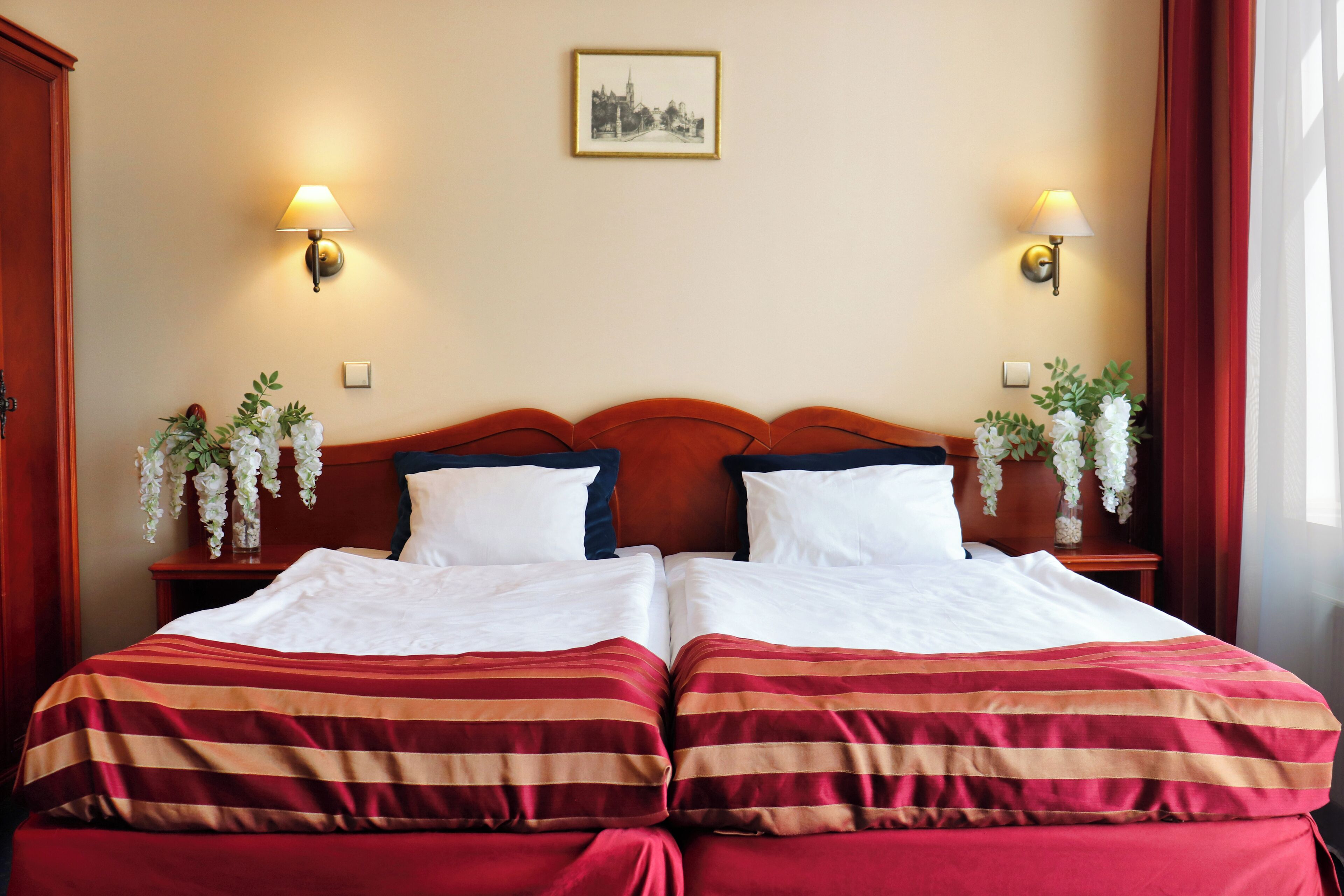 A double bed with striped bedding, two bedside tables with lamps, and decorative flowers.