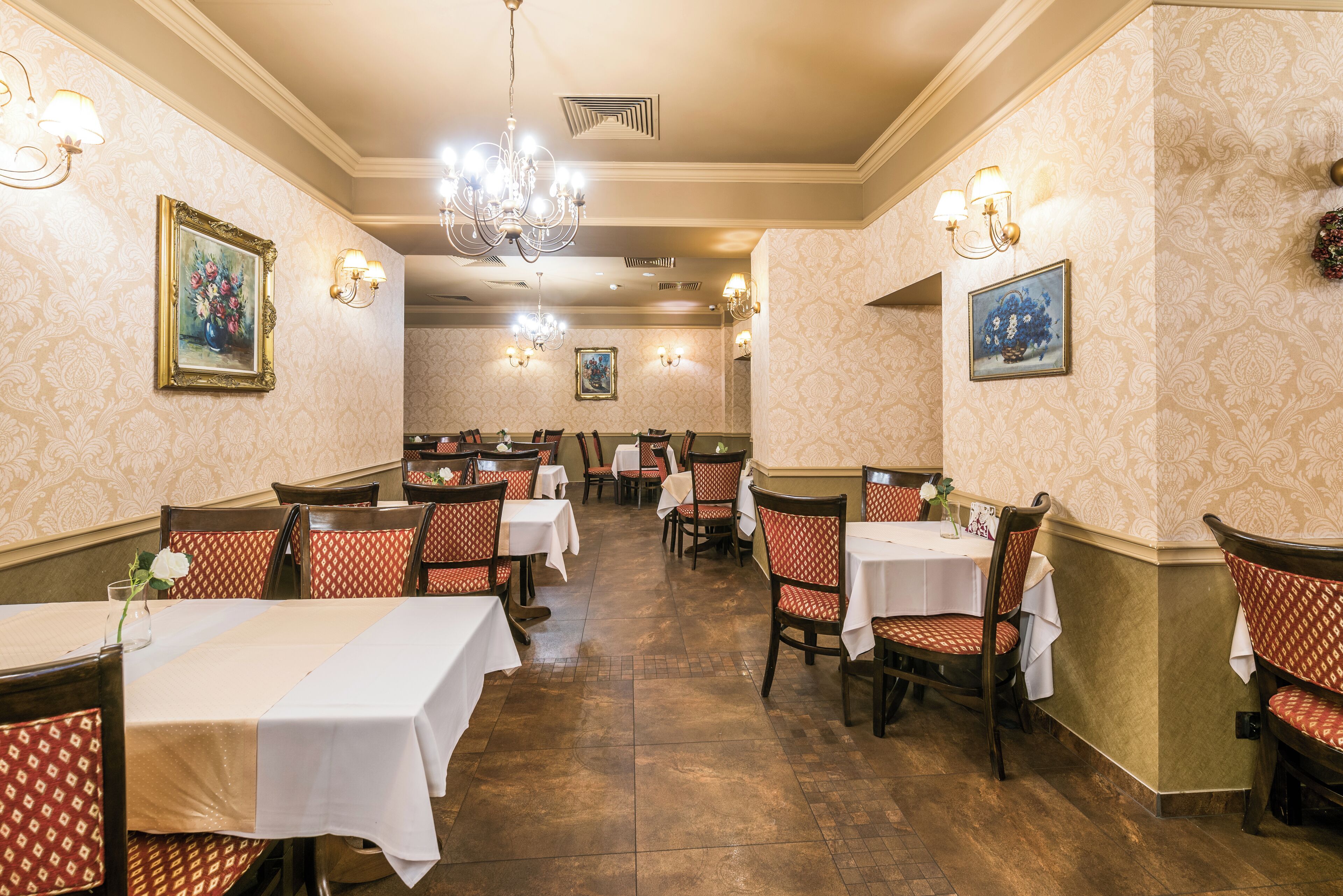 Un comedor con mesas y sillas, candelabros e iluminación empotrada.