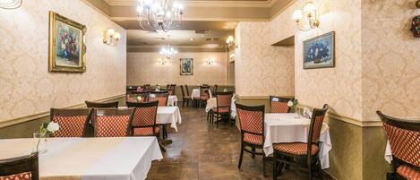 Un comedor con mesas y sillas, candelabros e iluminación empotrada.