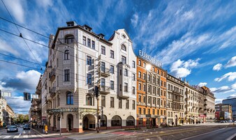 Um edifício histórico com vários andares, detalhes arquitetônicos ornamentados e uma placa de destaque com a inscrição 