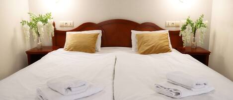 A double bed with white linens, two pillows, and folded towels on each side.