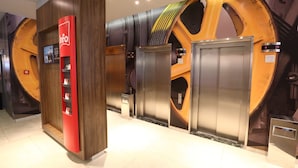 A modern elevator area with a red information kiosk and large cylindrical wall decorations. - ibis Buenos Aires Obelisco (Buenos Aires)