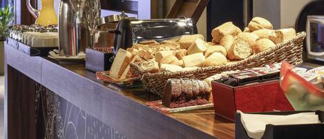 Un buffet proposant une variété de pains, de viennoiseries et un espace dédié au café.