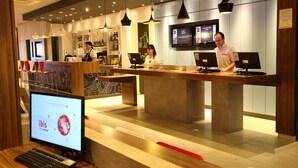 A hotel reception area with multiple computer monitors, a reception desk, and a seating area with chairs. - ibis Buenos Aires Obelisco (Buenos Aires)