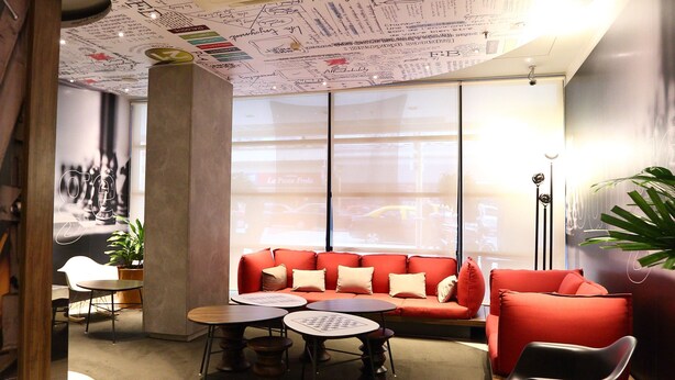 A modern lounge area with a red sofa, round tables, and a ceiling covered in handwritten notes and drawings. - ibis Buenos Aires Obelisco (Buenos Aires)