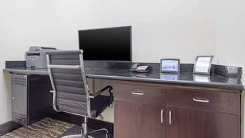 Un escritorio moderno de oficina con monitor de computadora, impresora y teléfono.