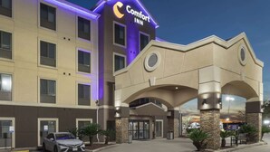 A Comfort Inn hotel with a modern facade, a parking lot, and a car parked in front. - Comfort Inn Orange I-10 (Orange)