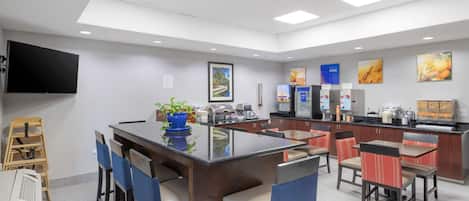 A modern restaurant with a central island, bar seating, and a flat-screen TV on the wall.
