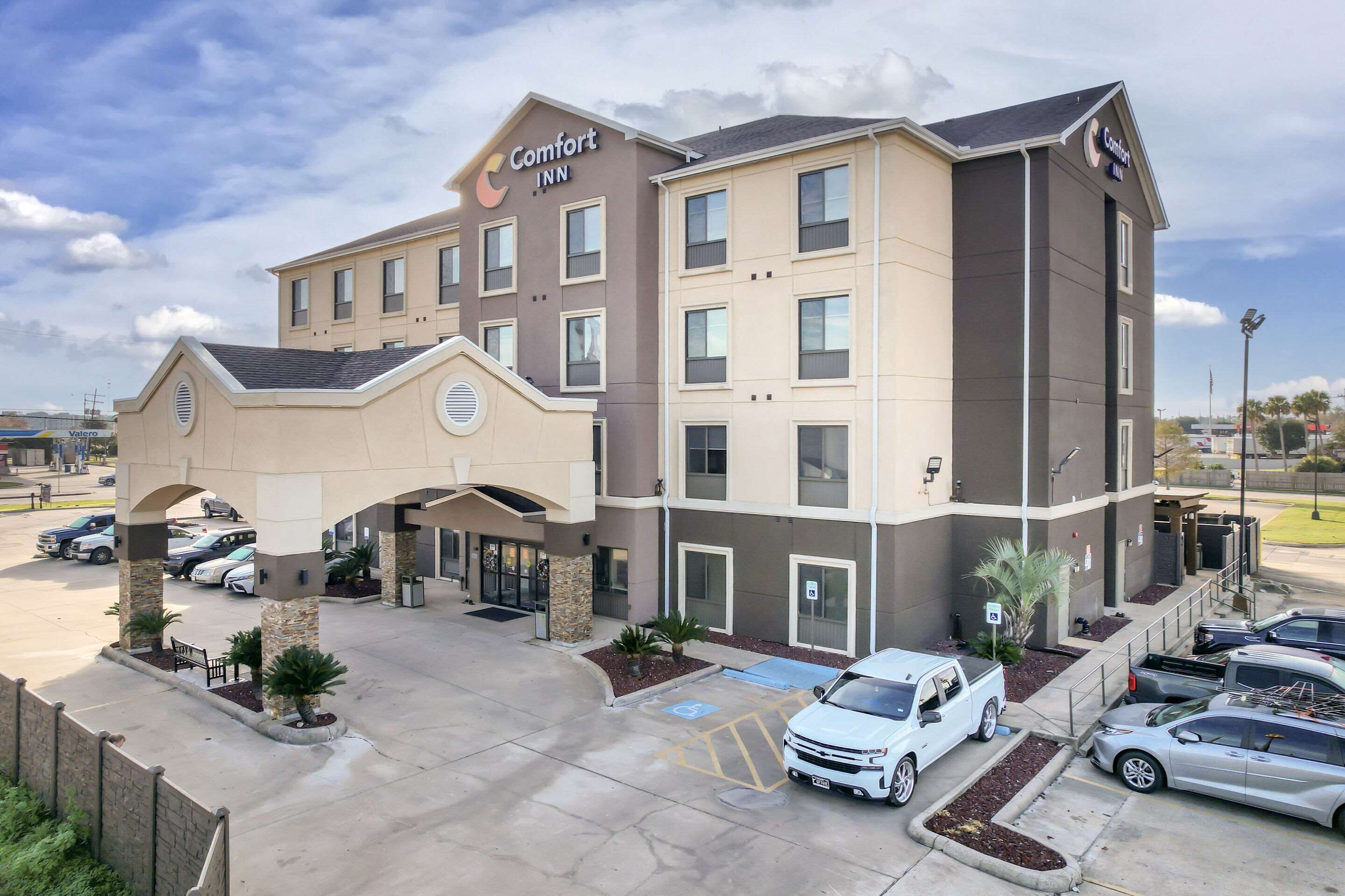 A Comfort Inn hotel with a central entrance, multiple parking spaces, and a clear sky.