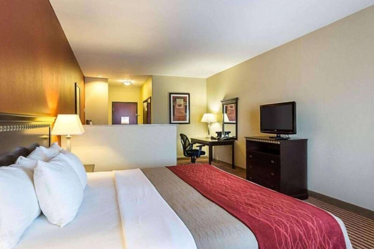 A hotel room with a bed, a desk, a television, and a mirror.