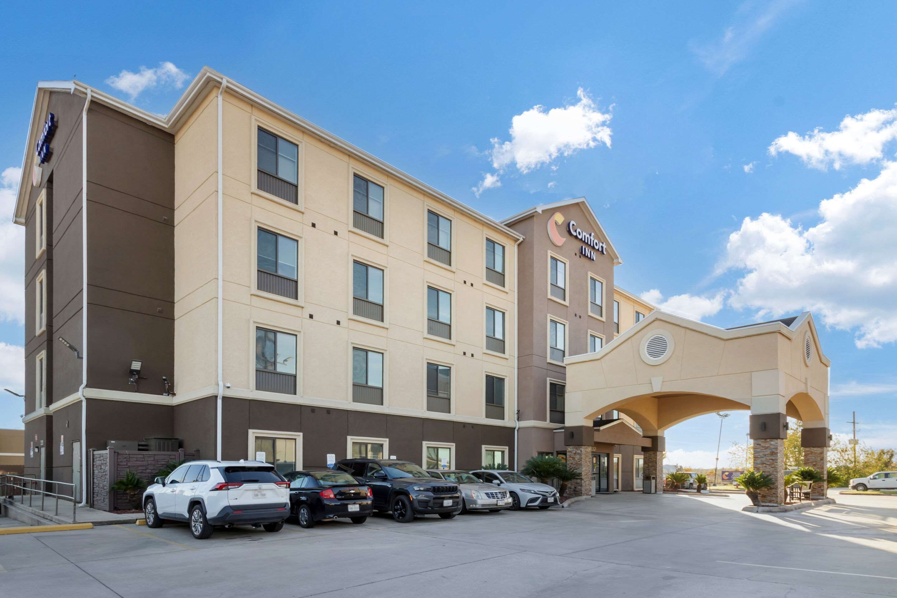 Un hotel Comfort Inn con un estacionamiento y varios coches aparcados al frente.