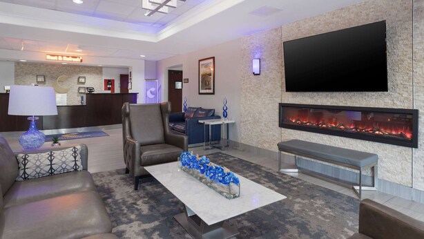 A modern hotel lobby with a reception desk, seating area, flat-screen TV, and a fireplace. - Comfort Inn Orange I-10 (Orange)