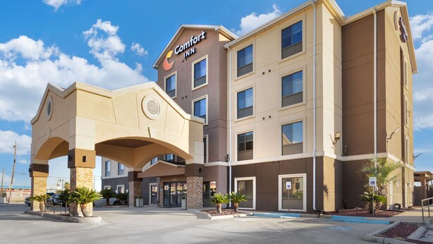 A Comfort Inn hotel with a modern design, featuring a prominent entrance with a covered walkway, multiple floors, and a parking area with palm trees.