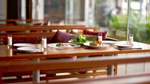 A restaurant with wooden tables and benches, plates with food and drinks, and a view of greenery outside. - Hotel CLASKA (Tokyo)