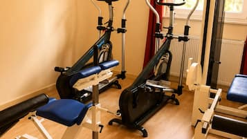 A gym with cardio machines, a bench, and a wall-mounted picture.