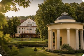 A classical building with a central dome and a symmetrical facade, surrounded by a well-manicured garden. - Kulturhotel Kaiserhof (Bad Liebenstein)