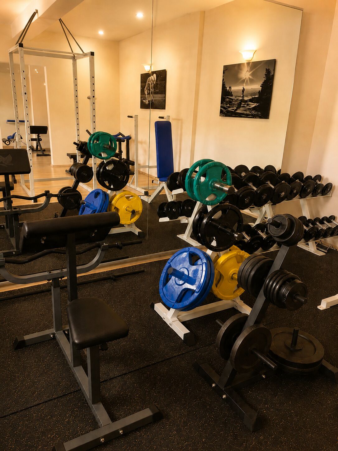 Una palestra con attrezzature per sollevamento pesi, panche e uno specchio.