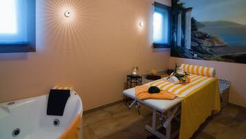 A spa room with a massage table, a bathtub, and a mural of a coastal landscape.