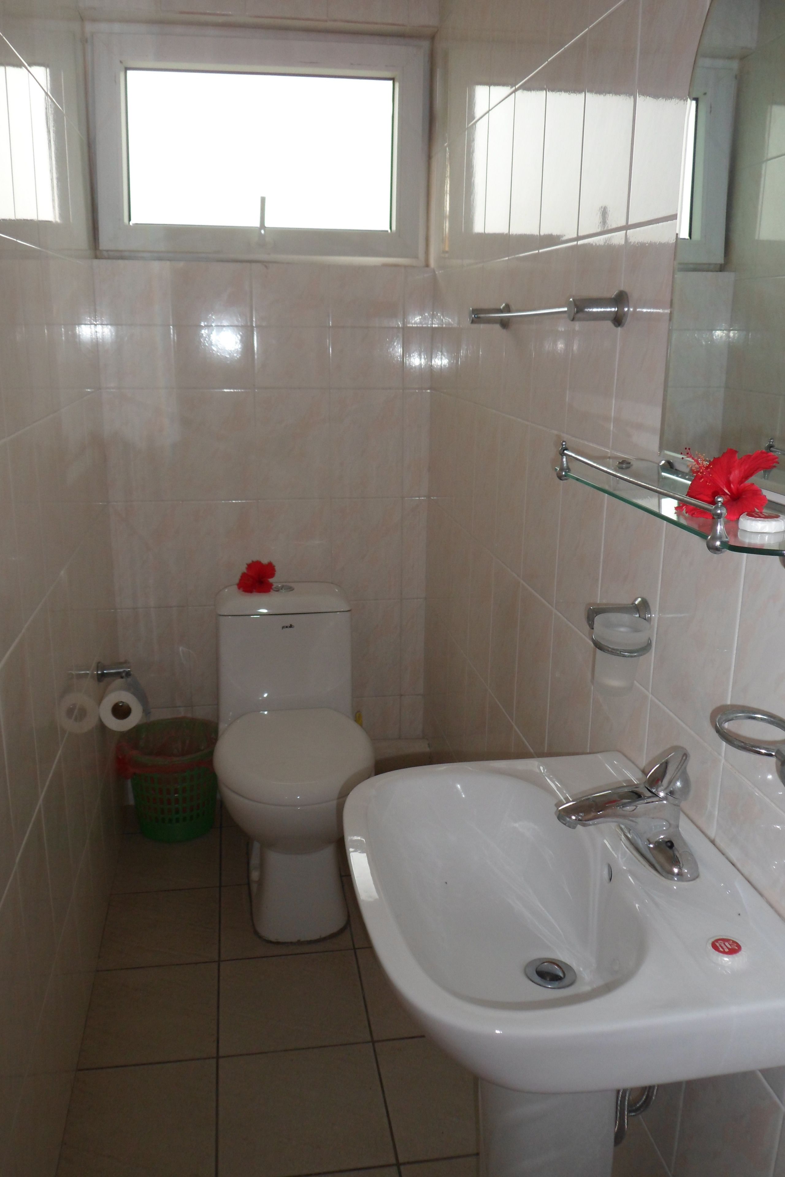 A bathroom with a toilet, sink, and a window above the toilet.
