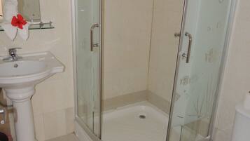 A bathroom with a glass-enclosed shower, a pedestal sink, and a toilet.