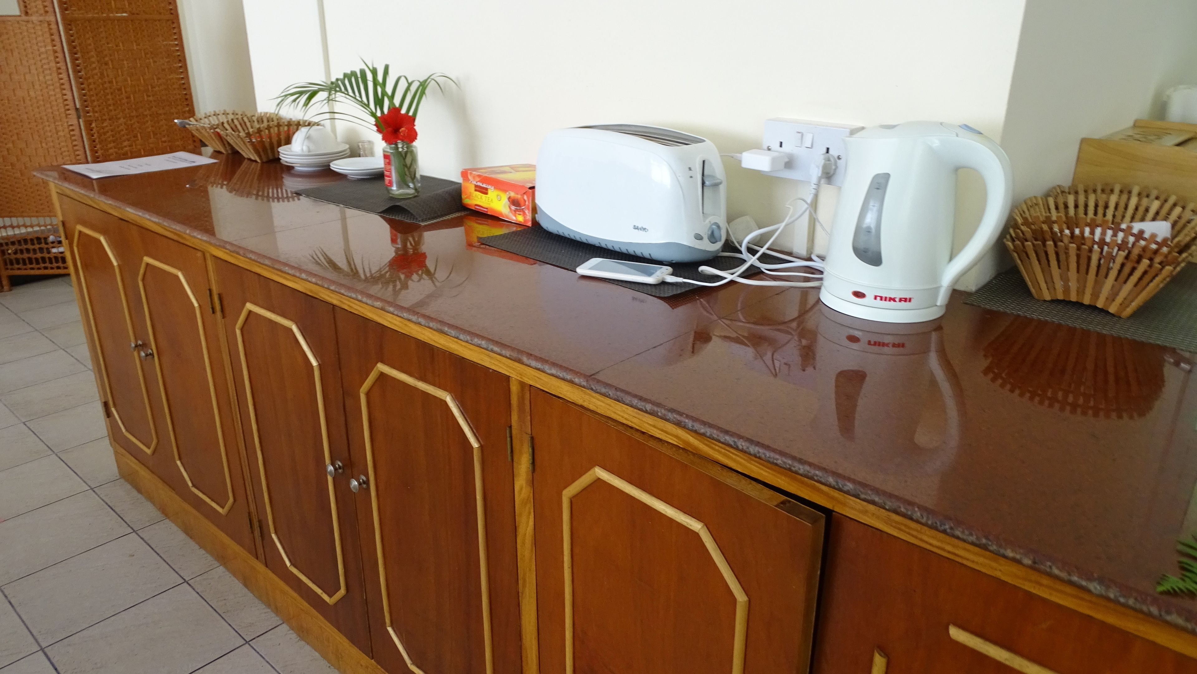 Una encimera de cocina con un tostador, un hervidor y un teléfono inteligente.