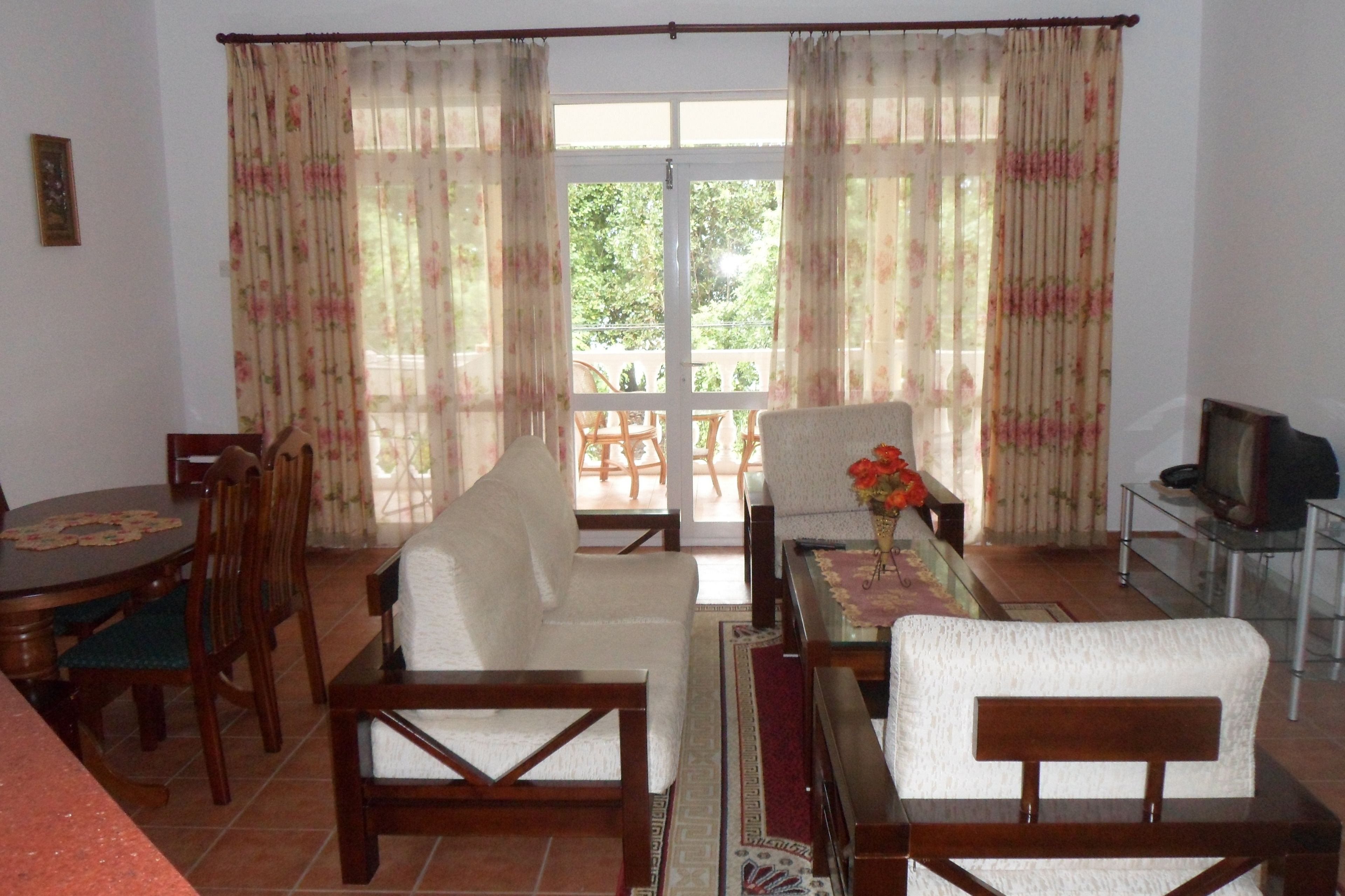 A living room with a sofa, chairs, a TV, and a dining table.