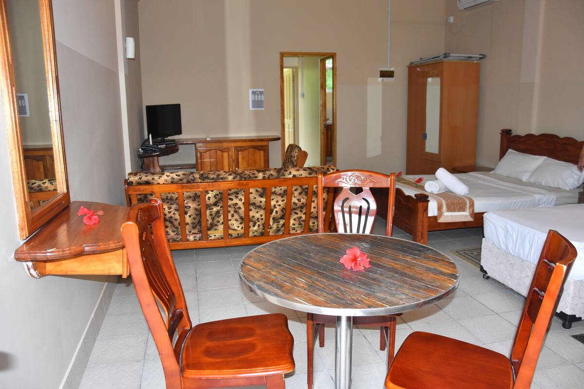A hotel room with a bed, a desk with a chair, a round table with chairs, and a wardrobe.