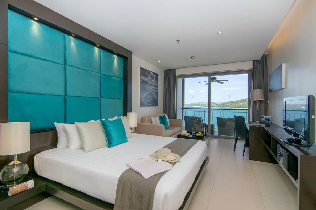 Habitación de hotel moderna con una cama grande, un escritorio, una silla y un balcón con vistas.