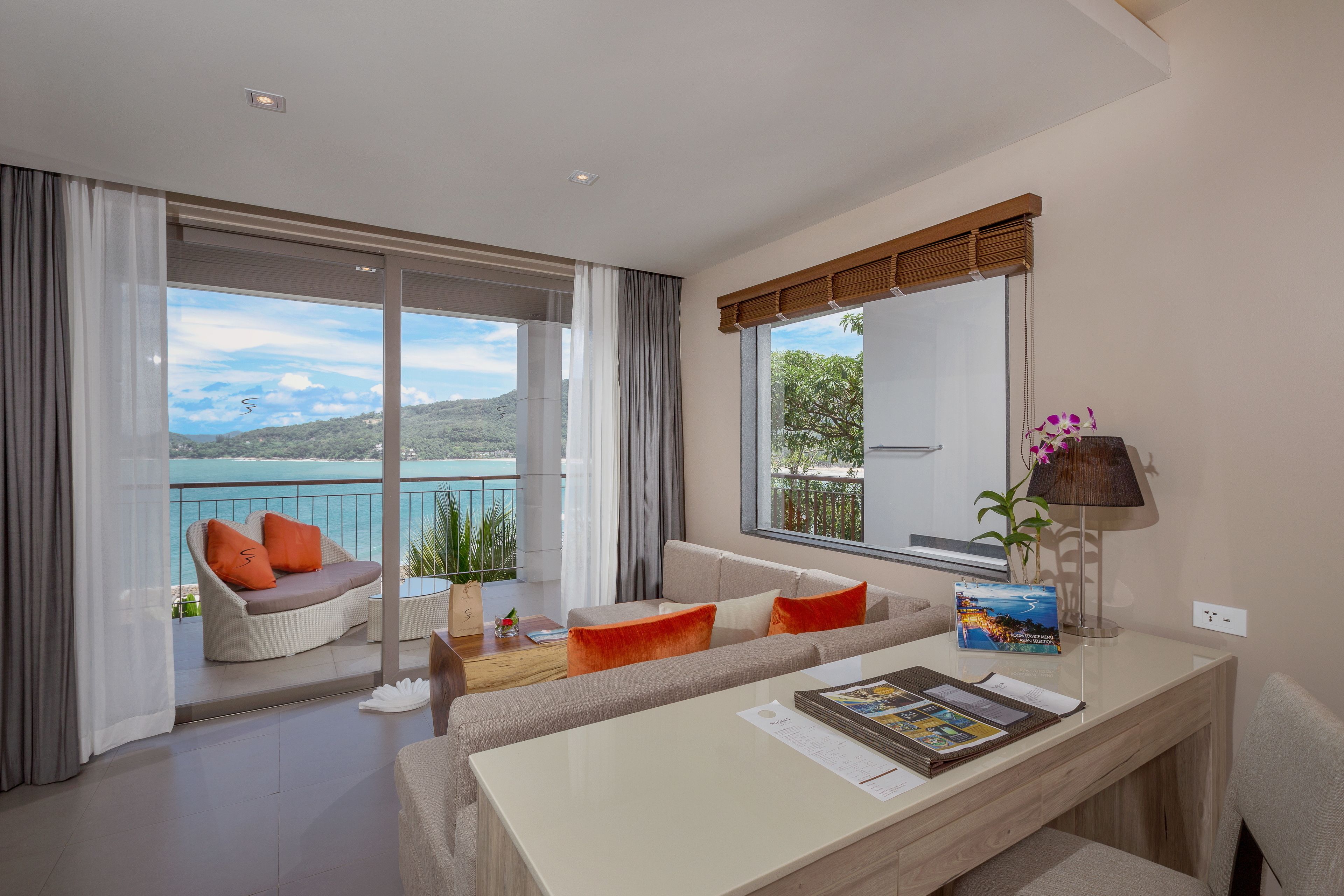 Una sala de estar moderna con balcón, ventanas amplias y vista al mar.