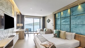 Une chambre d’hôtel moderne, dotée d’un grand lit, d’un bureau, d’une télévision et offrant une vue sur la mer.