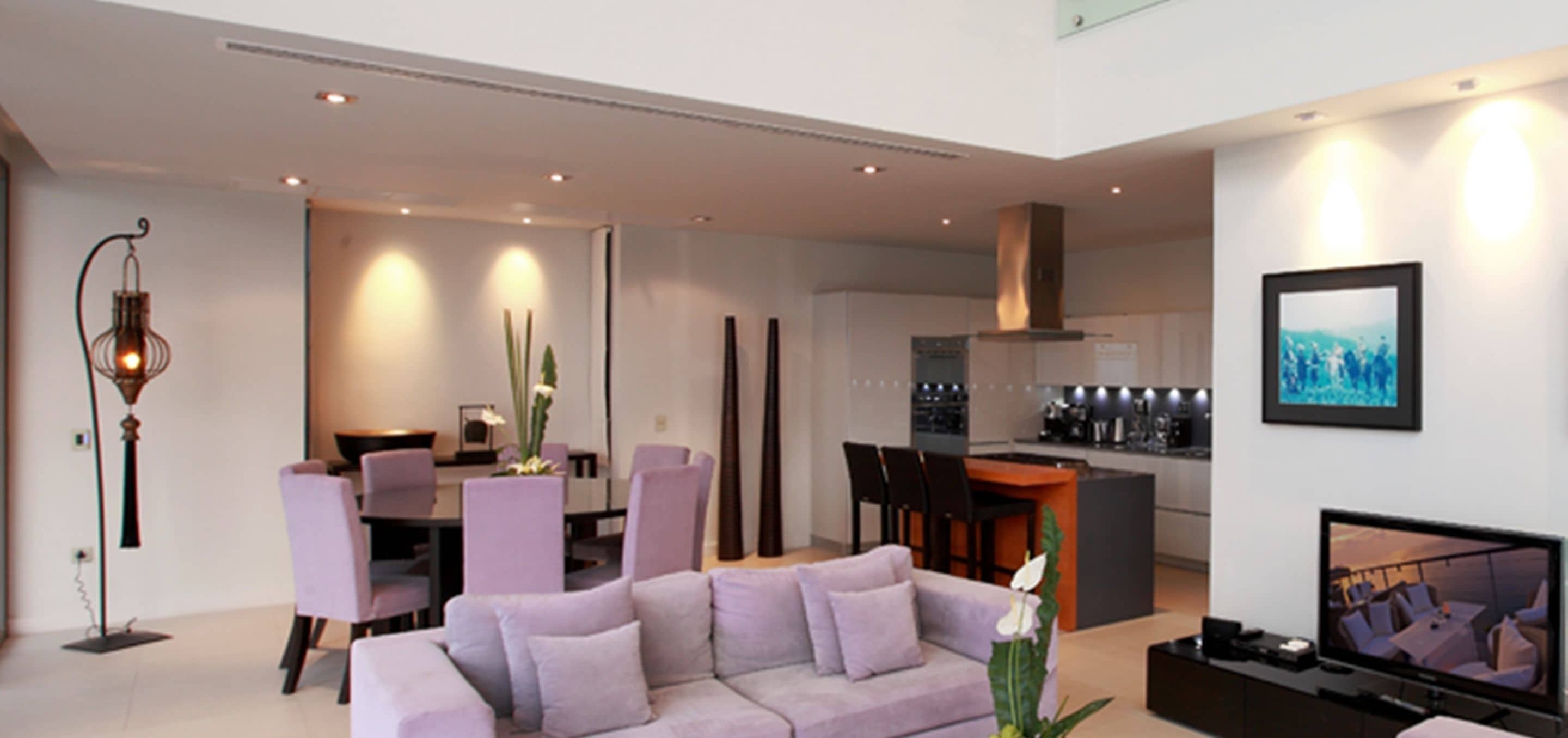 A modern living room with a sofa, dining area, and kitchen.