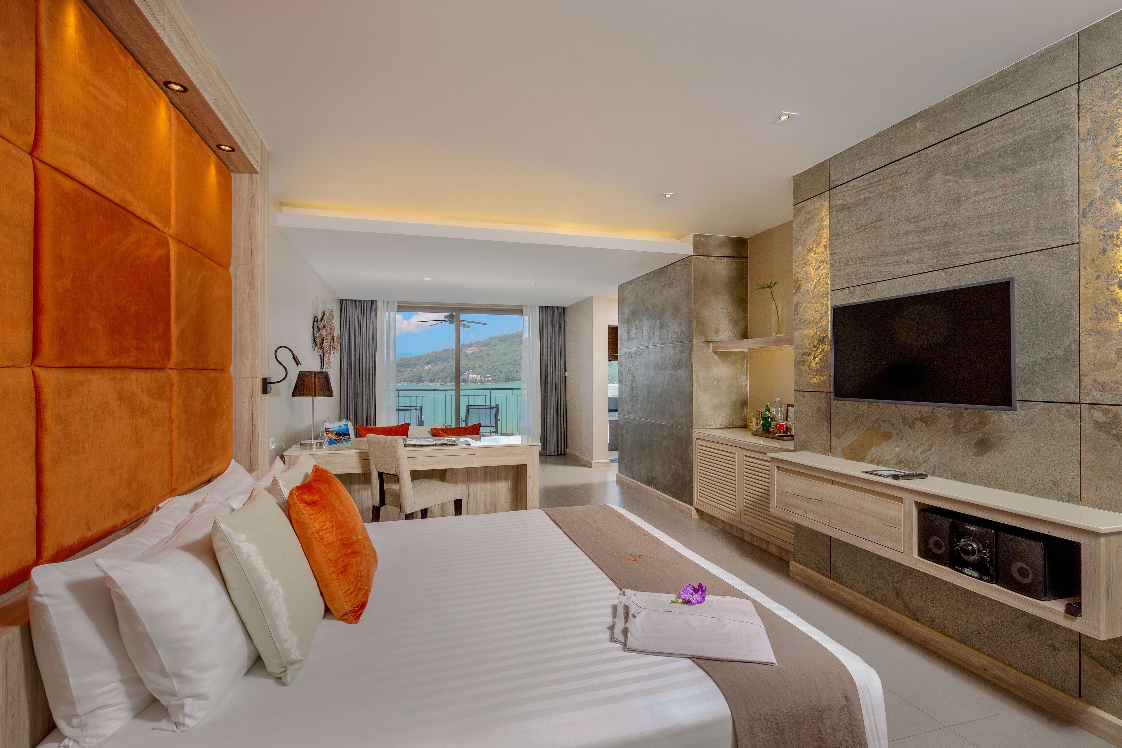 A modern hotel room with a large bed, a desk, and a TV mounted on the wall.