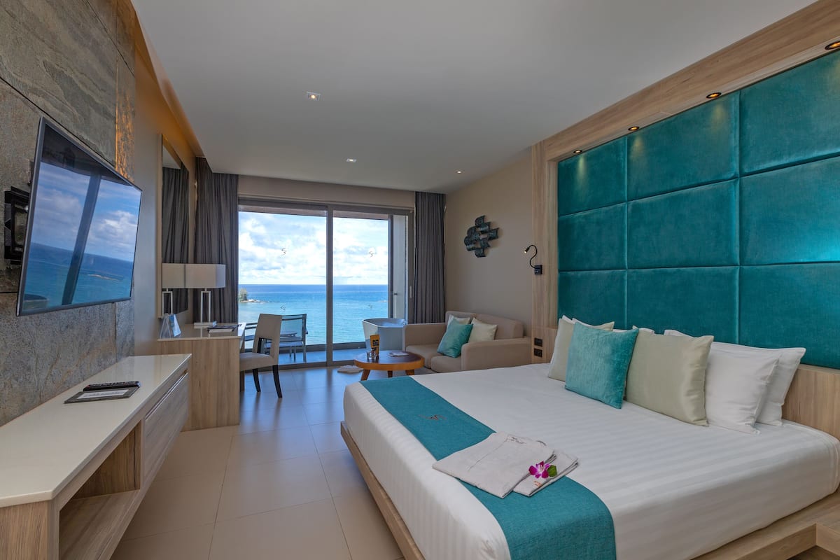 Una habitación de hotel moderna con una cama grande, un escritorio y vistas al océano.