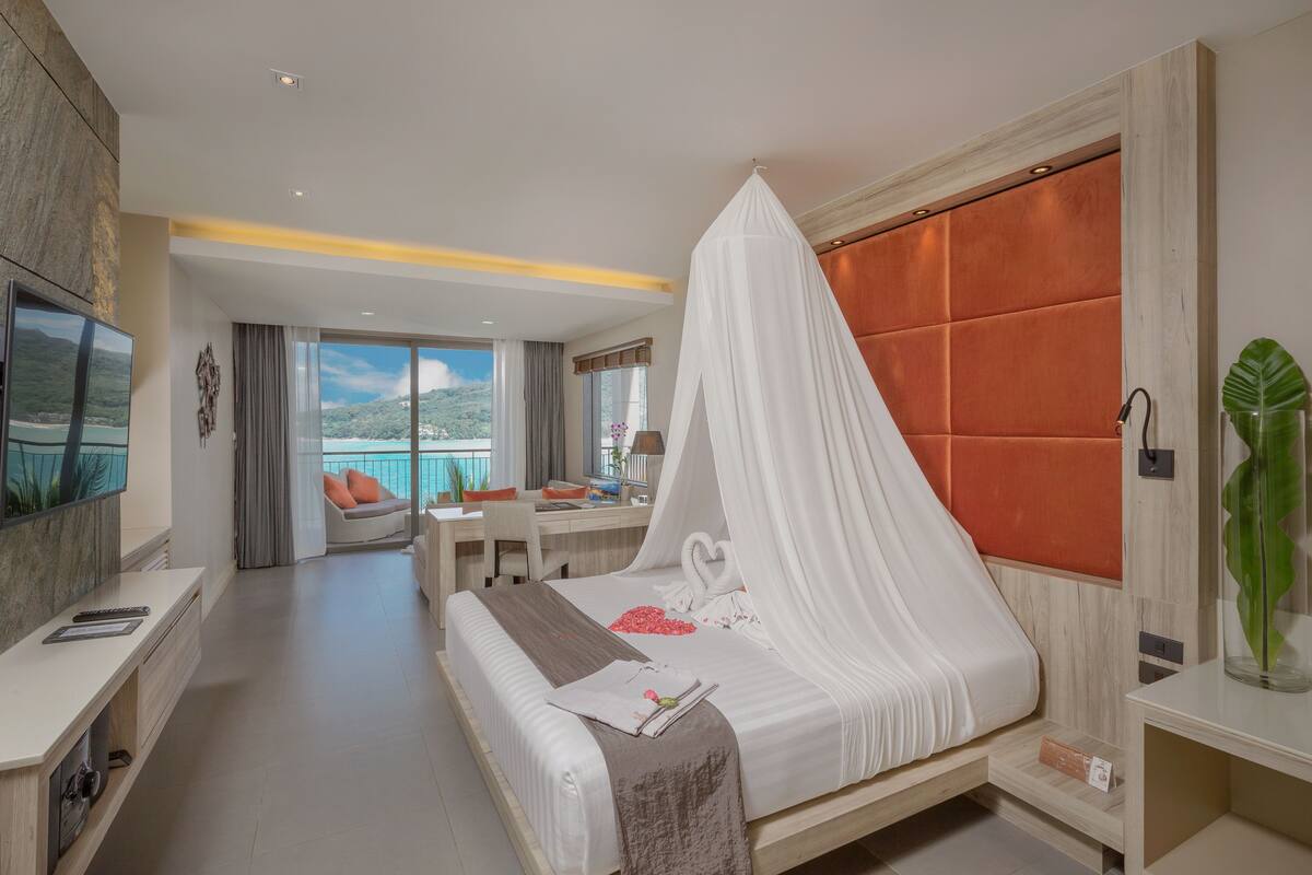 Una habitación de hotel moderna con una cama grande, un escritorio, una silla y un televisor.