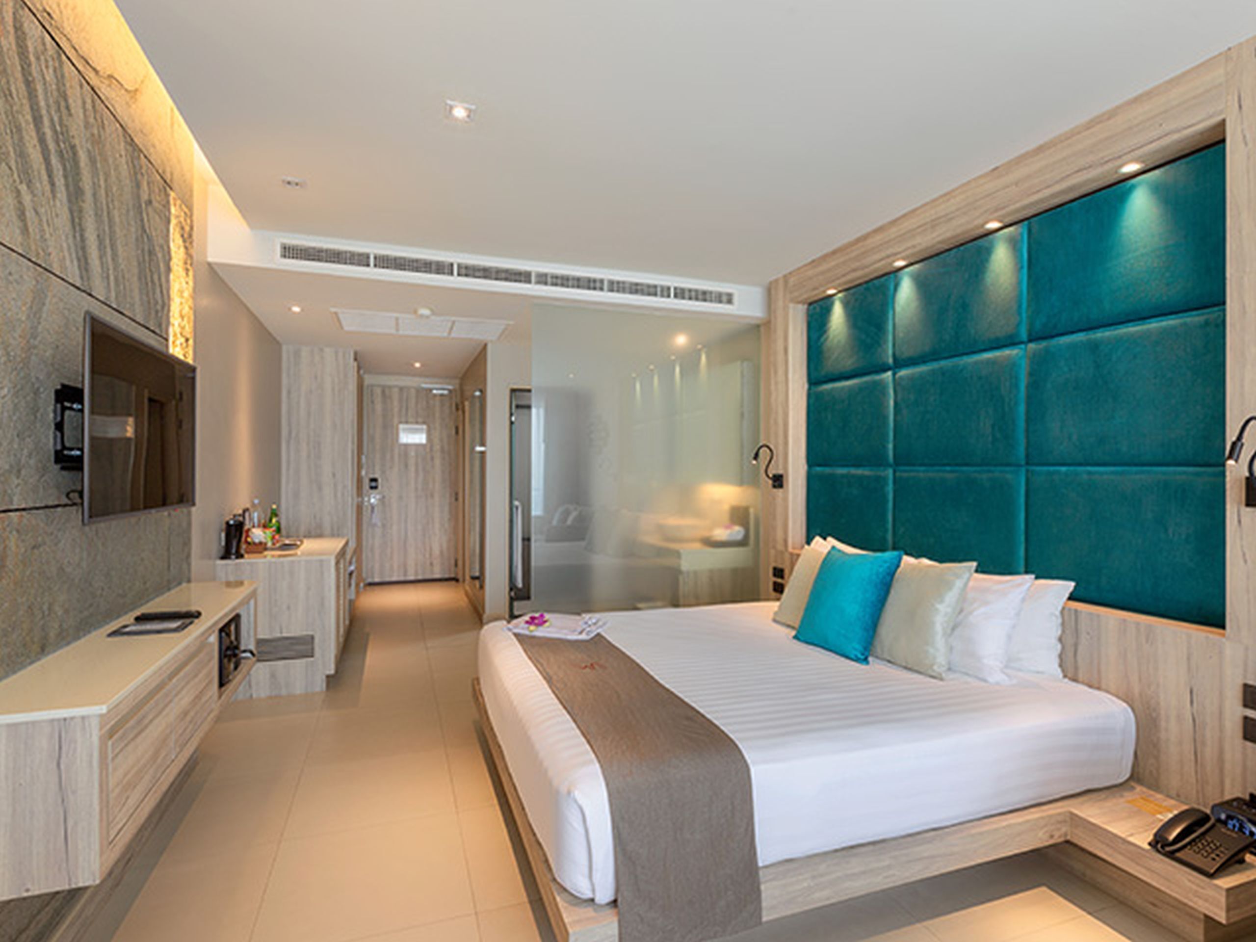 Ein modernes Hotelzimmer mit einem großen Bett, einem Schreibtisch, einem Fernseher und einem Badezimmer.