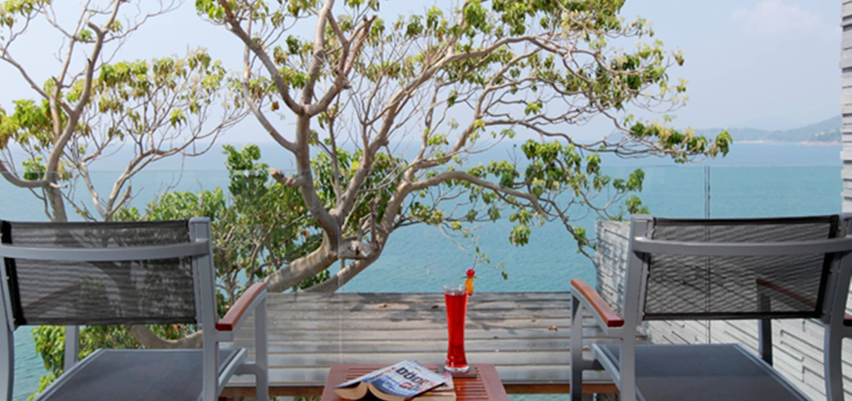 A balcony with two chairs, a table, and a drink.