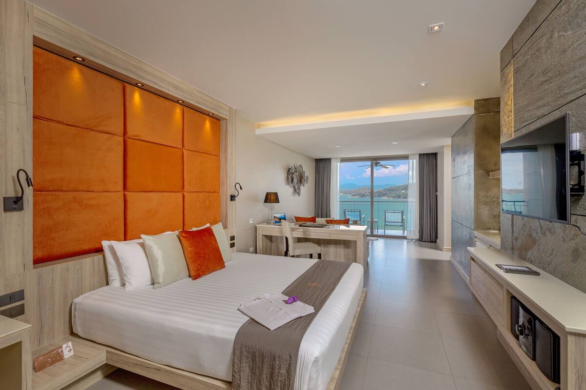Una habitación de hotel moderna con una cama grande, un escritorio y un televisor.