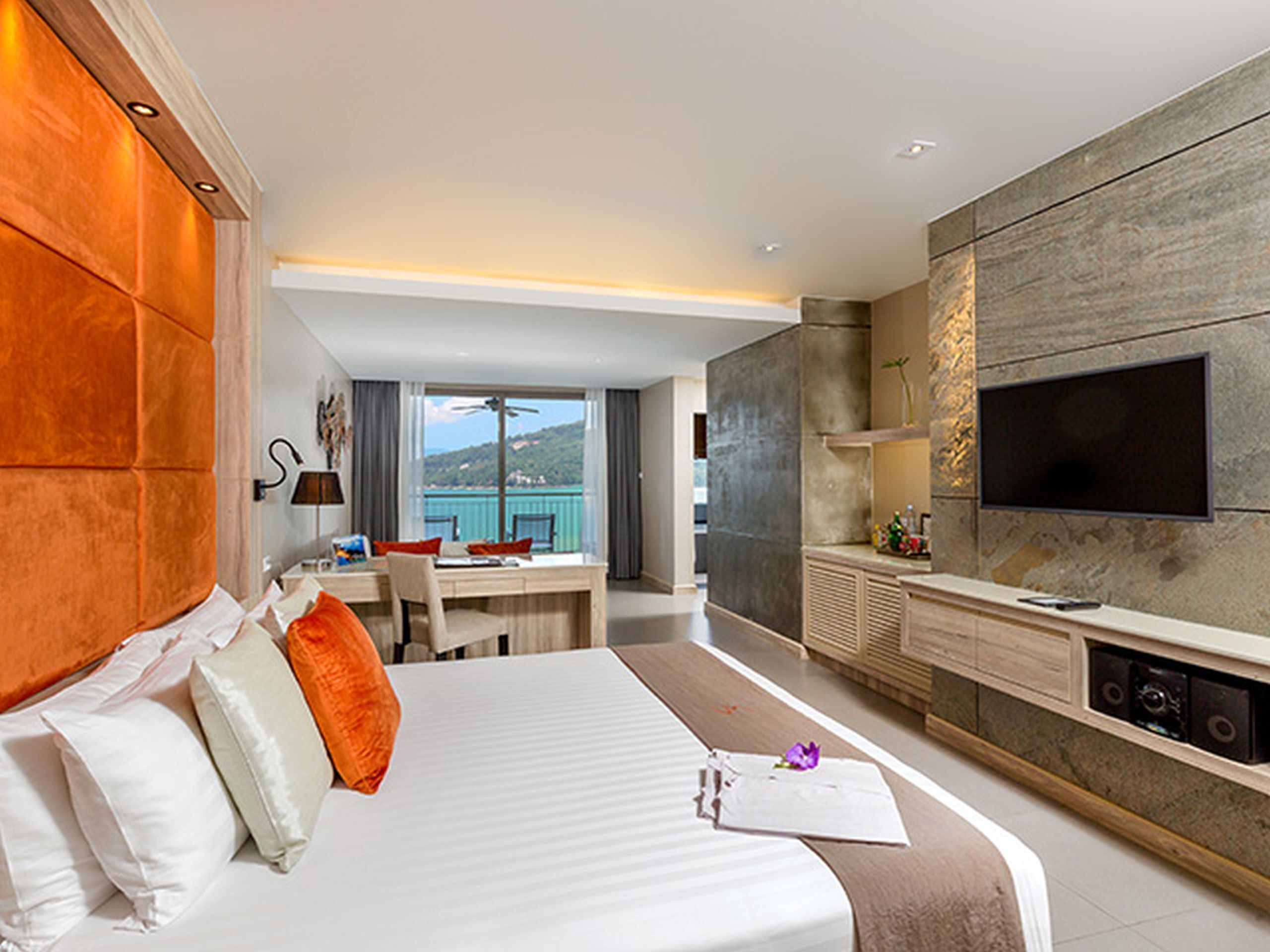 Ein Hotelzimmer mit Bett, Schreibtisch, Fernseher und Meerblick.