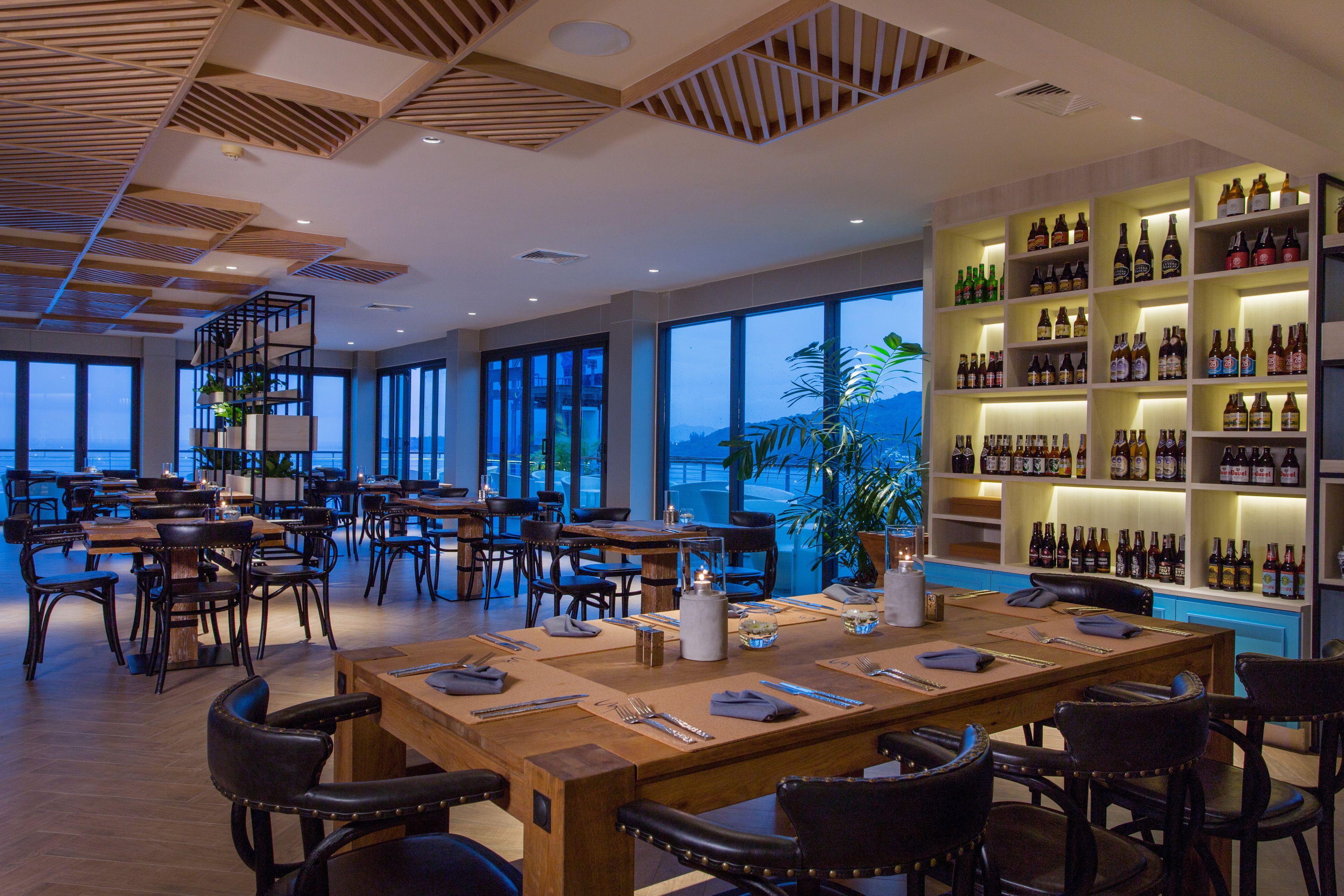 A restaurant with multiple dining tables, chairs, and a large wine display.