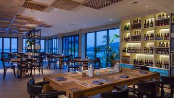 A restaurant with multiple dining tables, chairs, and a large wine display.