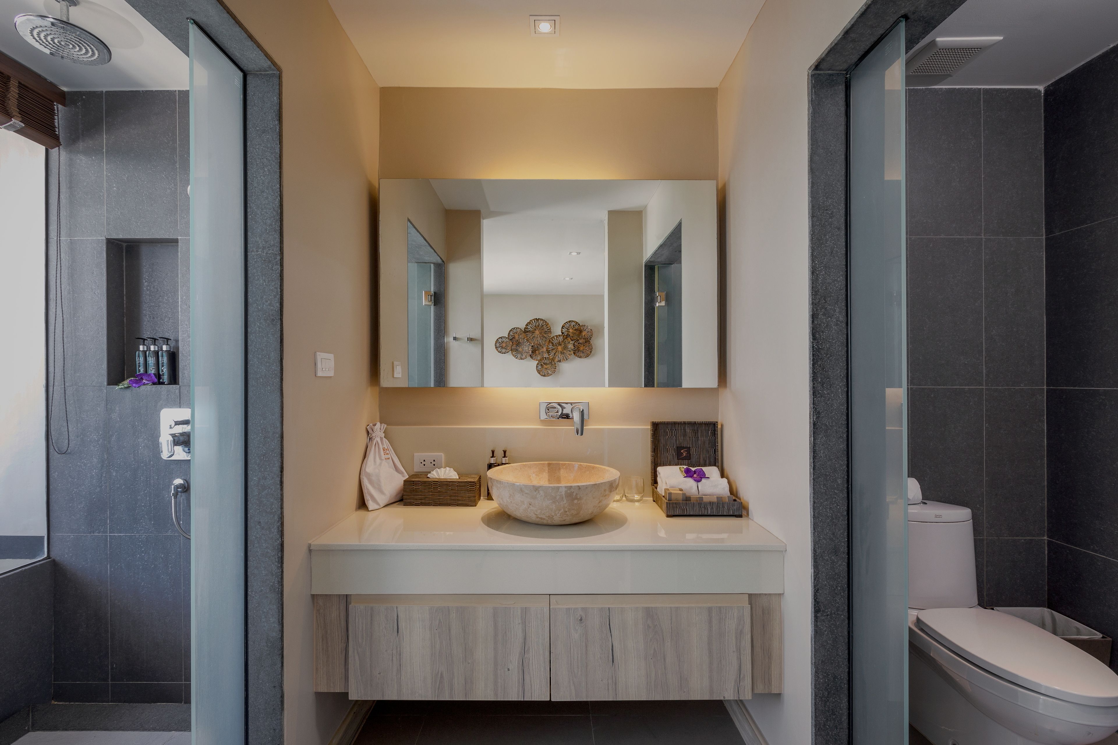 Een moderne badkamer met een grote spiegel, een rond wastafel en een toilet.