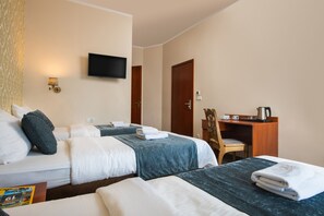 A hotel room with two beds, a desk, a chair, a television, and a wall-mounted lamp. - Aparthotel Globus (Kraków)