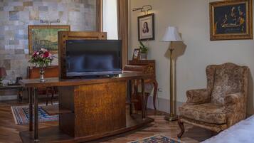 A living room with a wooden entertainment center, a sofa, a chair, a lamp, and a painting on the wall.