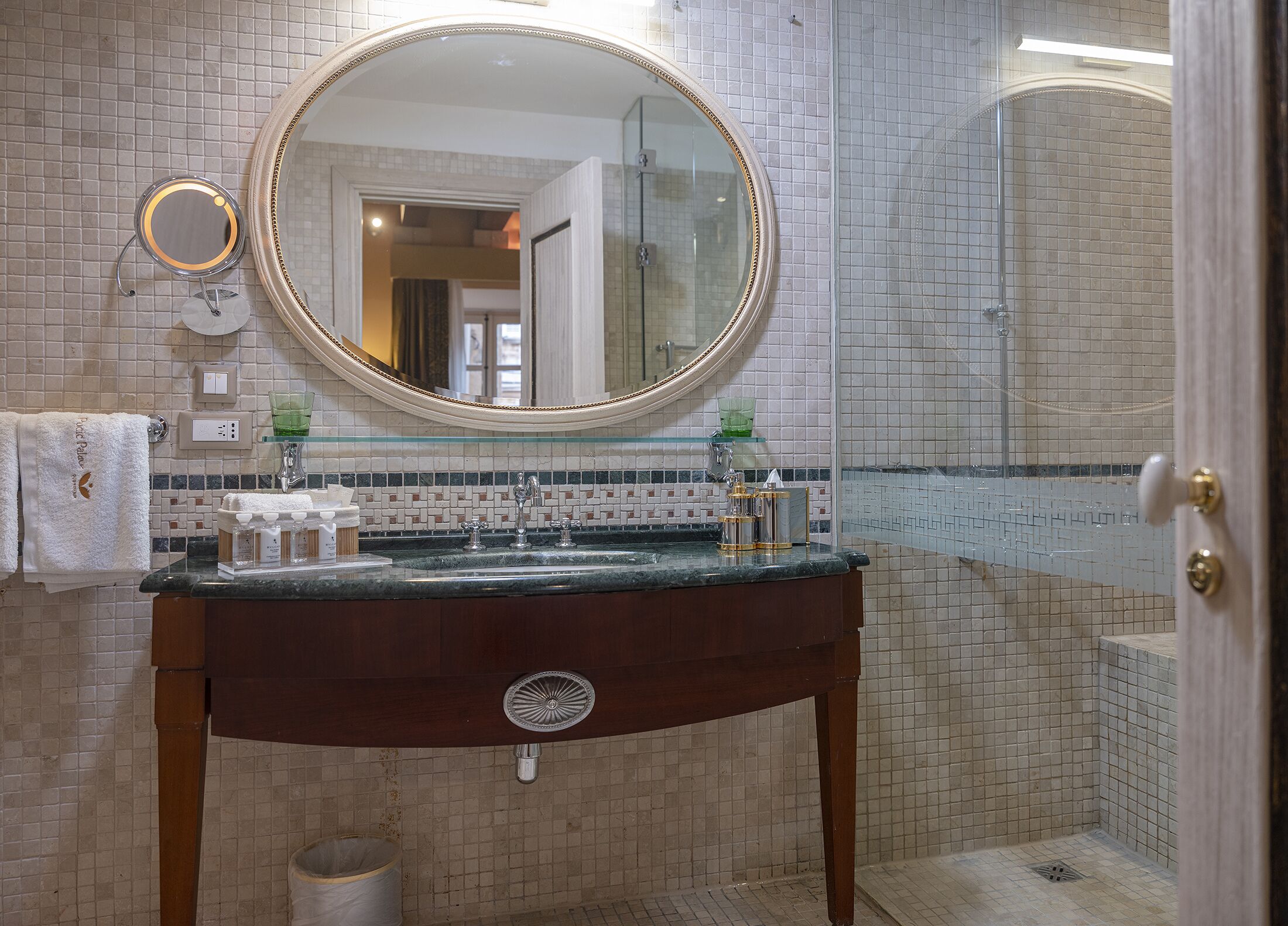 A bathroom with a marble sink, a large mirror, and a shower area.
