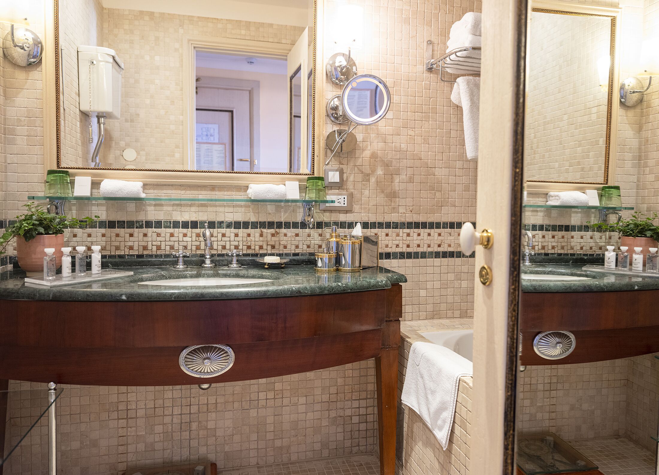 Een badkamer met twee wasbakken, een spiegel, een handdoekhouder en een douche.