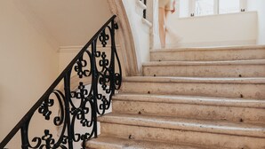 Una amplia escalera con barandillas negras decoradas y un ventanal grande en la parte superior.