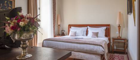 Un dormitorio ordenado con una cama de madera, lámparas de noche, un jarrón floral y una alfombra estampada.