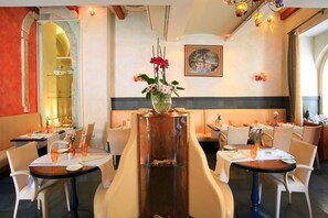 A restaurant with round tables, white chairs, and a central decorative vase with flowers. - The Pucic Palace (Dubrovnik)