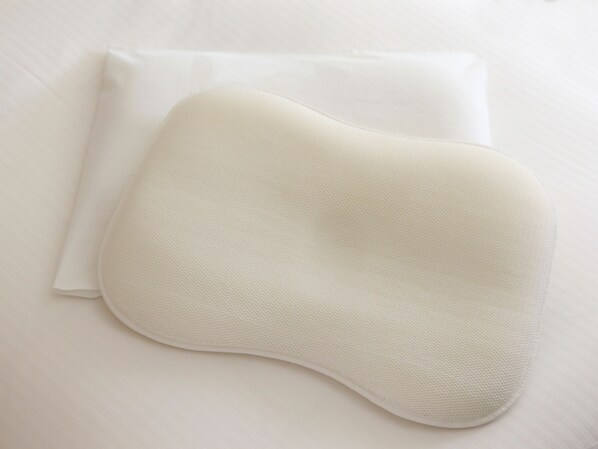A white pillow and a white pillowcase on a white bed.